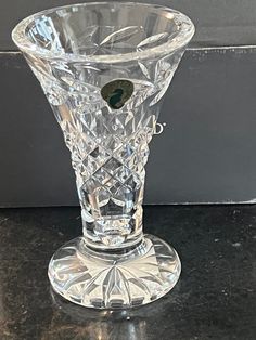 a clear glass vase sitting on top of a black table next to a gray wall