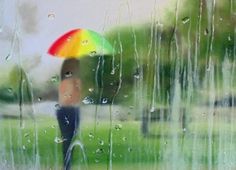 a person holding an umbrella standing in the rain on a rainy day with green grass and trees behind them