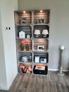 an empty room with several shelves on the wall and pictures on the floor in front of it