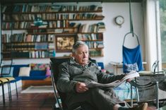 an older man sitting in a chair reading a newspaper