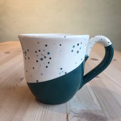 a green and white coffee cup sitting on top of a wooden table