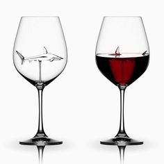 two wine glasses filled with red liquid and a shark in the glass are shown side by side