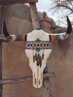 a cow skull with long horns and feathers on it