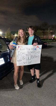 two girls standing next to each other holding a sign