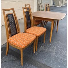 two chairs and a table with an orange patterned upholstered seat pad on the ground