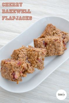 three pieces of food on a white plate with the words cherry bakewell flapjacks