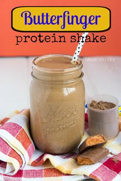 a glass jar filled with peanut butter protein shake next to a spoon on a checkered cloth