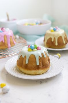 two bundt cakes with white icing and sprinkles on them sitting on plates