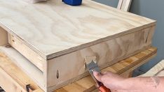 a person is using pliers to attach the drawers on a table top that has been made out of wood