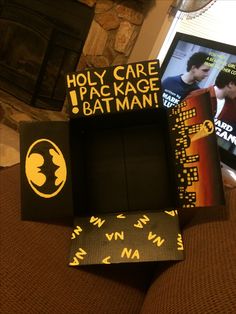 the batman movie box is sitting on top of a couch next to some posters and a fire place