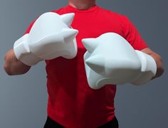 a man in a red shirt is holding two white cat shaped gloves on his hands