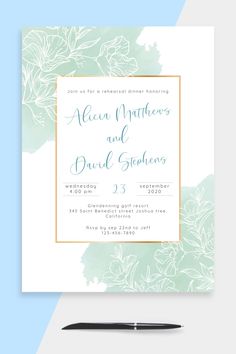 a wedding card with watercolor flowers on it and a pen in the foreground