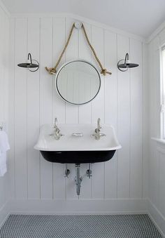 a white sink sitting under a mirror next to a wall mounted faucet in a bathroom