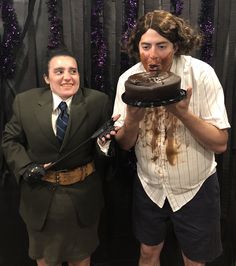 two people dressed up as zombies and holding a chocolate cake in front of them,