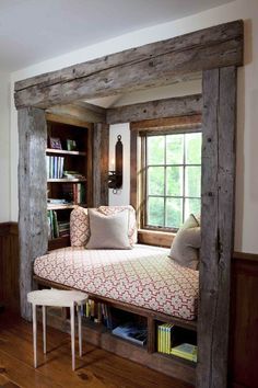 a window seat in the corner of a room with bookshelves and pillows on it