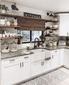 a kitchen filled with lots of white cupboards and counter top space next to a window