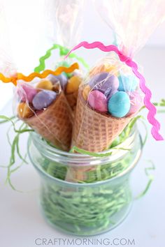 two ice cream cones with candies in them on a glass jar filled with candy