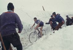 several people riding bikes in the snow on a mountain side with one person falling off his bike