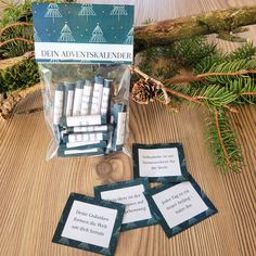 four cards with words on them sitting next to pine cones and evergreen needles in front of a christmas tree