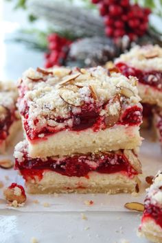 several pieces of cake sitting on top of a white plate next to berries and nuts