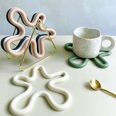 an assortment of decorative items on a table with spoons and coffee cup in the foreground