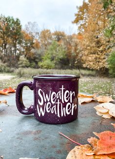 a purple coffee mug sitting on top of a table covered in leaves and fallen leaves