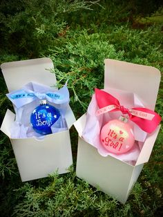 two white boxes with pink and blue ornaments in them sitting on the ground next to each other