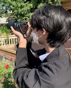 a person wearing a face mask and holding a camera up to the side with their hands