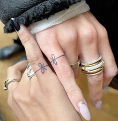 two people with matching rings on their fingers holding each other's hands and one has a clover tattoo on the middle finger