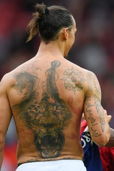 a man with tattoos on his back standing in front of an audience at a sporting event