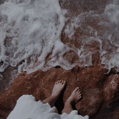 a person standing on top of a beach next to the ocean with their feet in the water