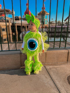 a little boy dressed in a green monster costume standing on the side of a building