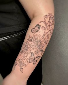 a woman's arm with flowers and butterflies tattoo on her left arm, which is black and white