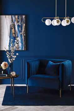 a living room with dark blue walls and gold accents on the ceiling, along with a velvet chair