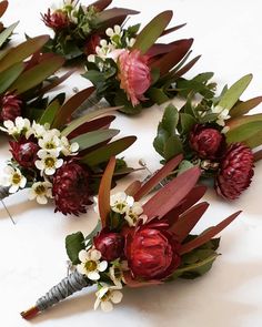 several bouquets of flowers are laid out on a white surface with green and red leaves