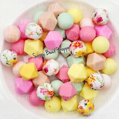 a white bowl filled with assorted candy candies and marshmallows in pastel colors