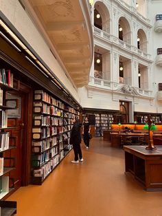 two people standing in front of a library filled with books