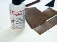 a bottle of leather glue sitting next to a piece of brown leather on top of a table