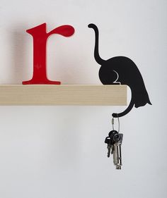 a wooden shelf with two keys and a red letter on the wall next to it