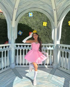 a woman in a pink dress is posing for a photo on a porch with flowers