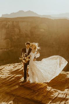 a bride and groom standing on top of a mountain