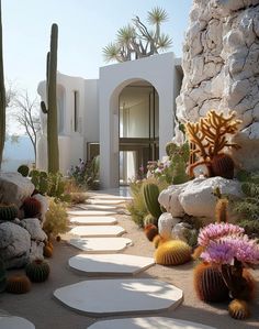 the entrance to a house with cactus and rocks around it, along with white circular steppings