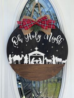 a nativity sign hanging on the front door of a house with a bow around it's neck