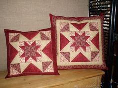 two red and white quilted pillows sitting on top of a wooden dresser next to each other