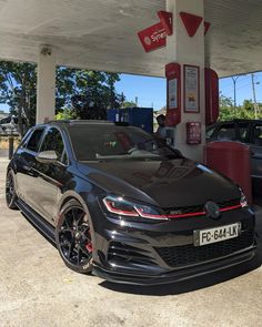 a black car parked in front of a gas station