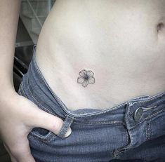 a woman's stomach with a small flower tattoo on the side of her belly