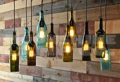 several wine bottles are hanging from the wall with light bulbs in them and one is empty