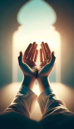 two hands reaching out to each other in front of an arch with light coming through