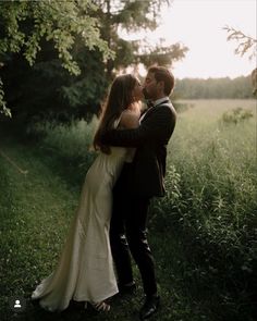 a bride and groom kissing in the grass