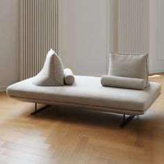 a white couch sitting on top of a hard wood floor next to a radiator